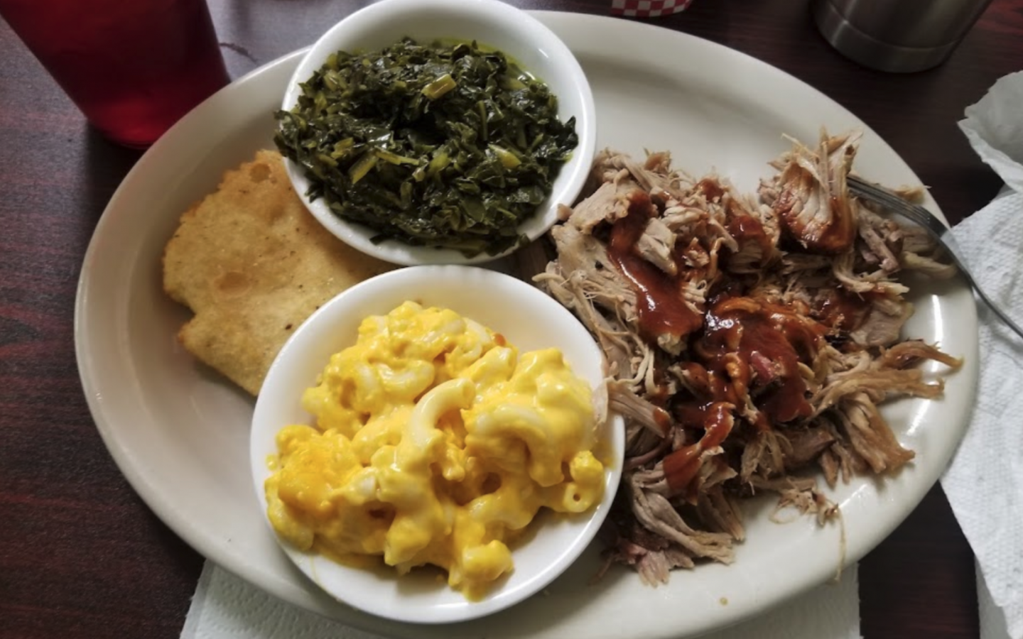 a plate with greens, homemade Mac and cheese, pulled pork with bbq sauce