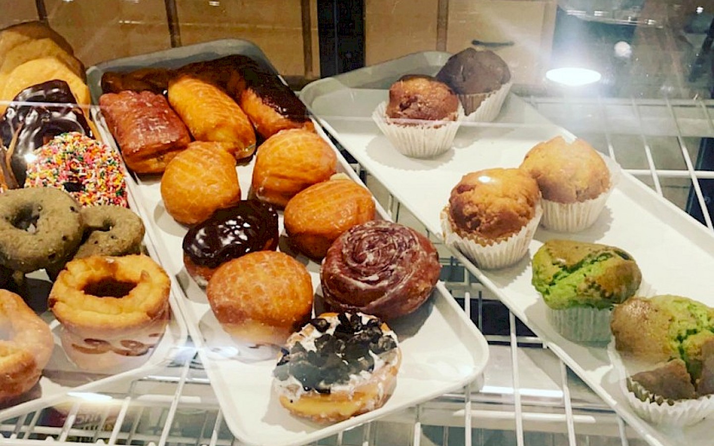 trays of locally made donuts and muffins at a coffee shop
