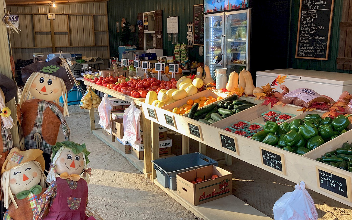 bell peppers, potatoes, squash, tomatoes, and an assortment of items on a long wooden display rack