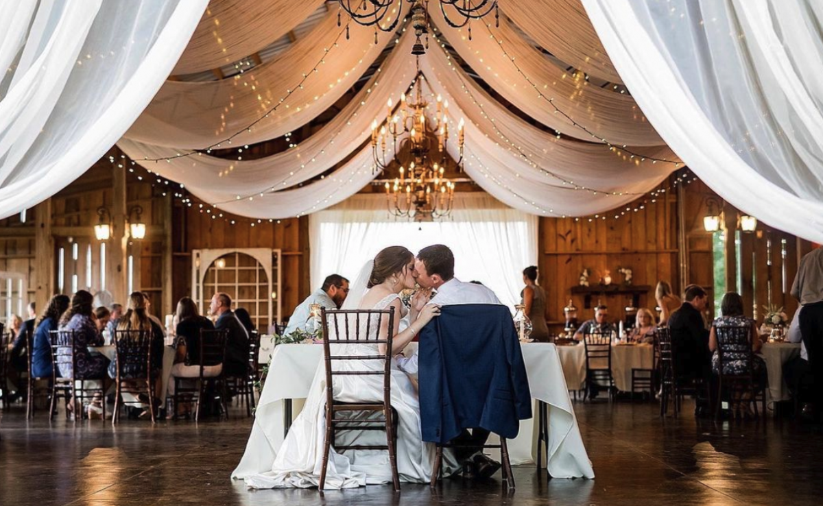 bride and groom seated, and kissing inside a beautifully decorated room