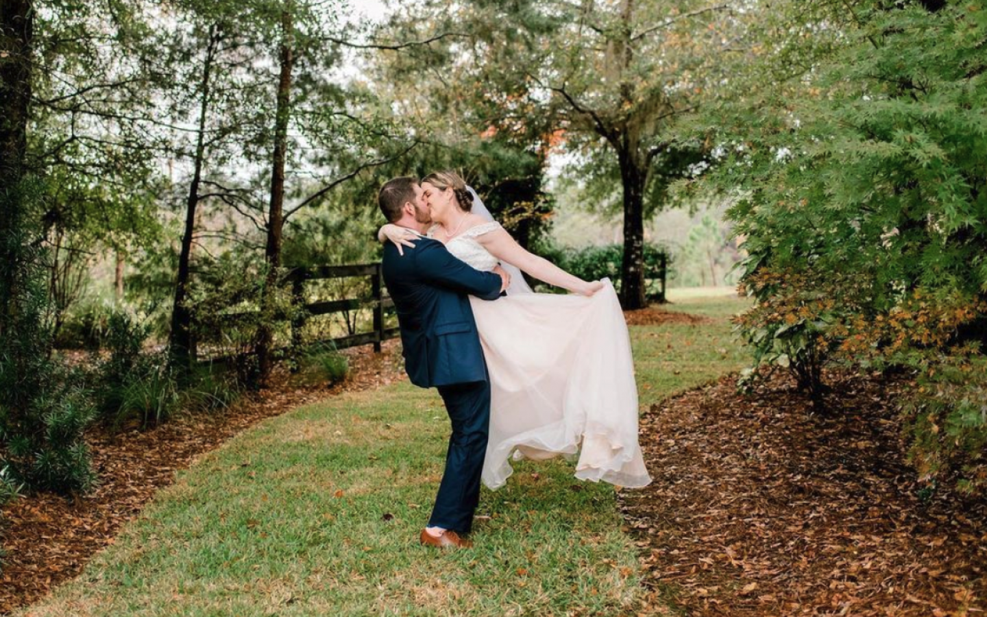 a bride and groom kissing, while standing on a spring trail
