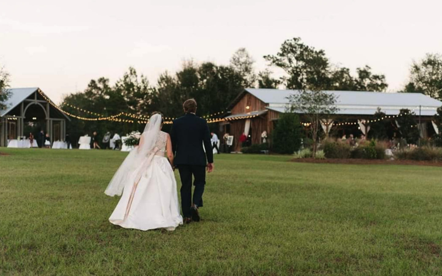 a bride and groom walk toward a large reception building