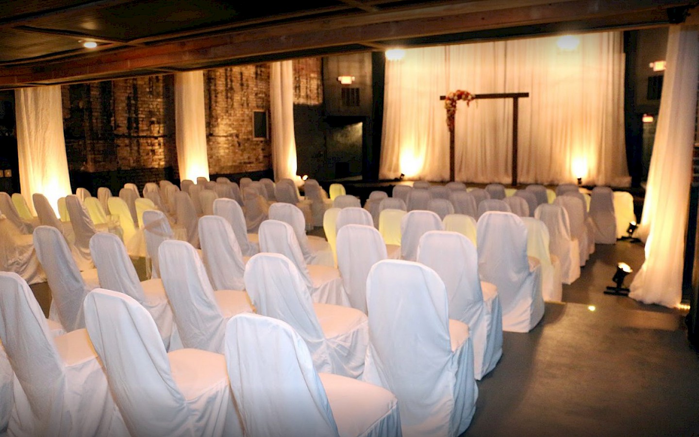 chairs, draped in white satin covers in a candle lit room prepared for a wedding ceremony