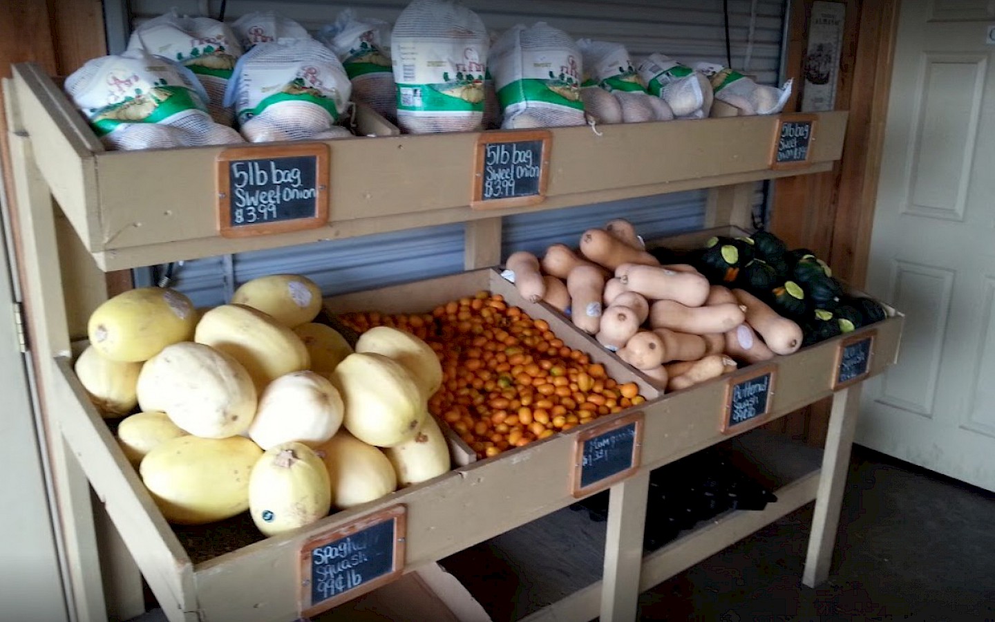 various vegetables, including squash, tomatoes, and sweet potatoes on display at the market