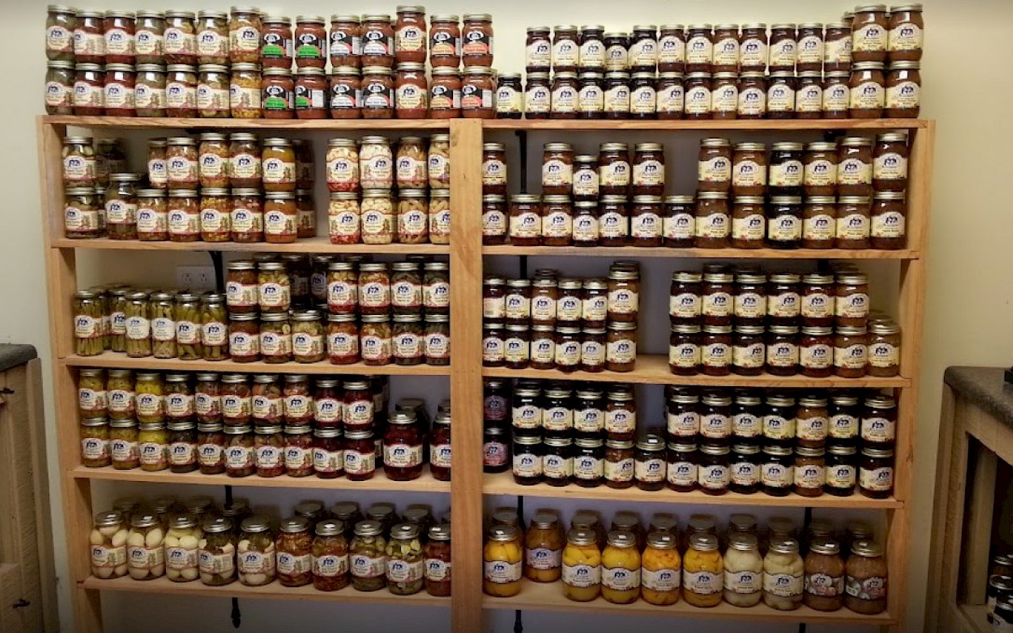 an assortment of jams, honey, syrup, jars displayed on wooden shelves