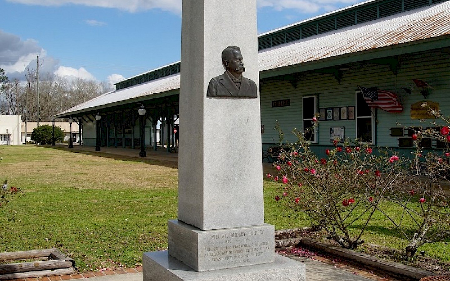statue on a green lawn of a town's founder in front of their museum