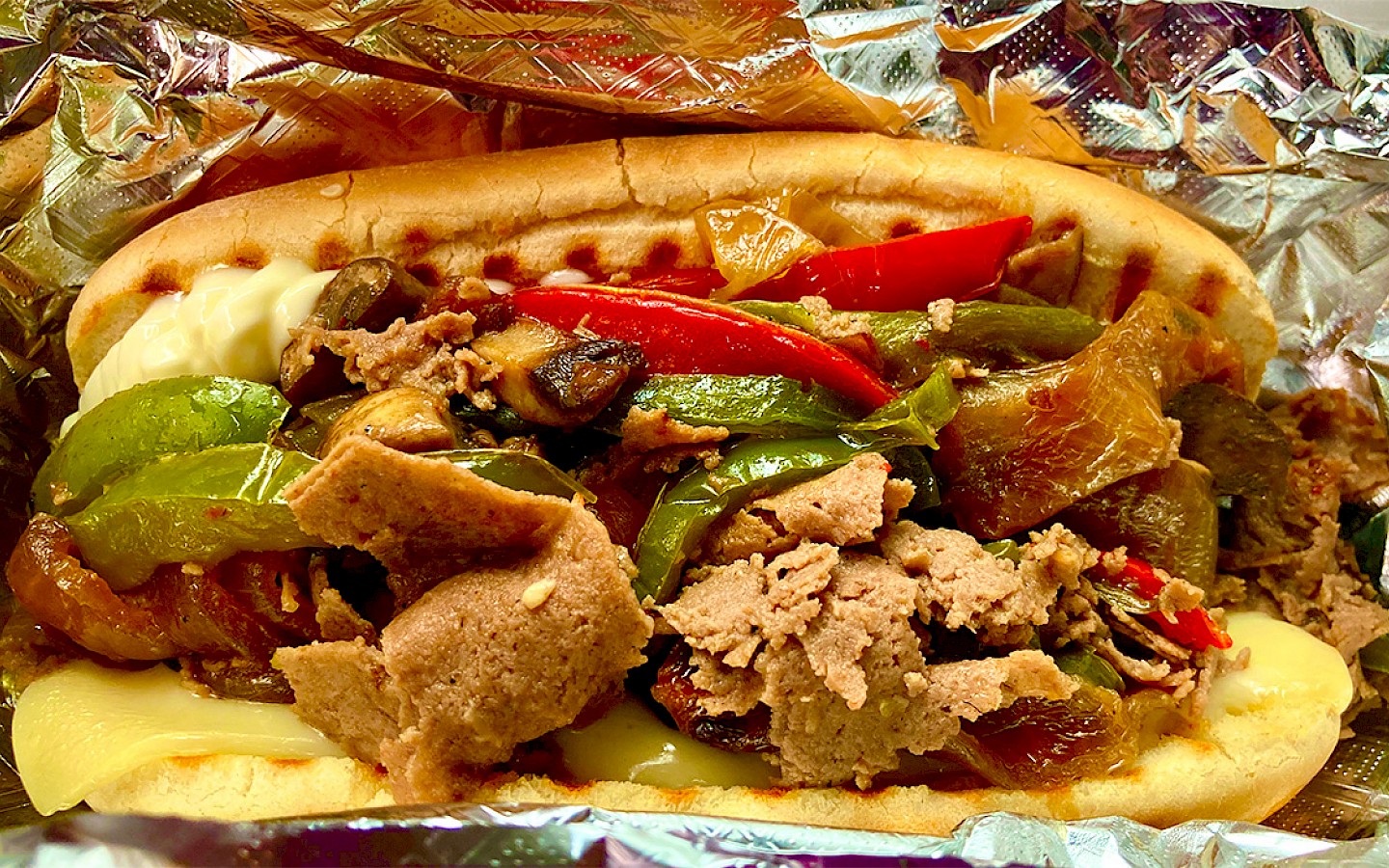 a phily cheesesteak sandwich, with beef, onions, bell peppers