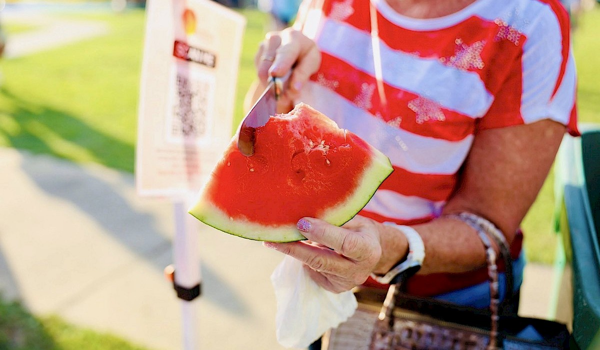 woman cutting into a slice of watermelon