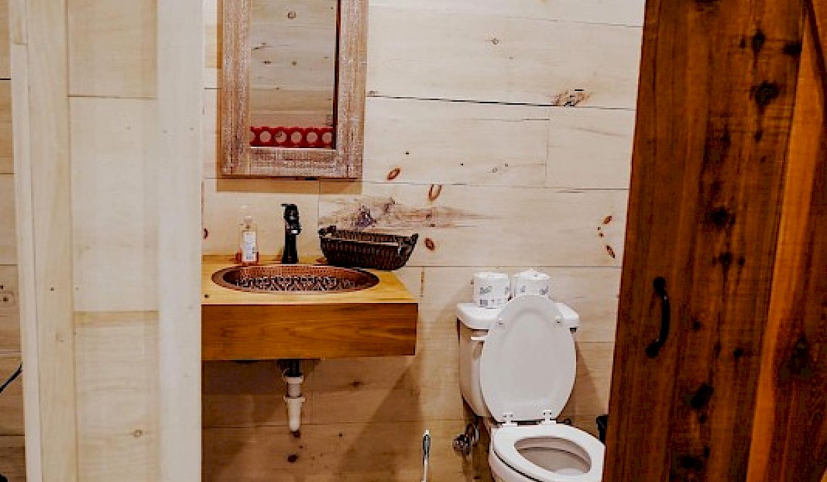 restrooms at the barn venue with wooden doors sink and mirror