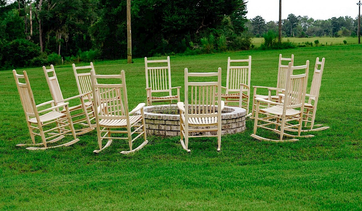fire pit with wooden rocking chairs on the grass lawn of the barn venue