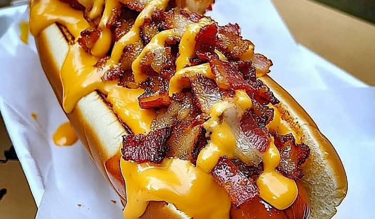 A hot dog with all the fixings sitting on a restaurant table