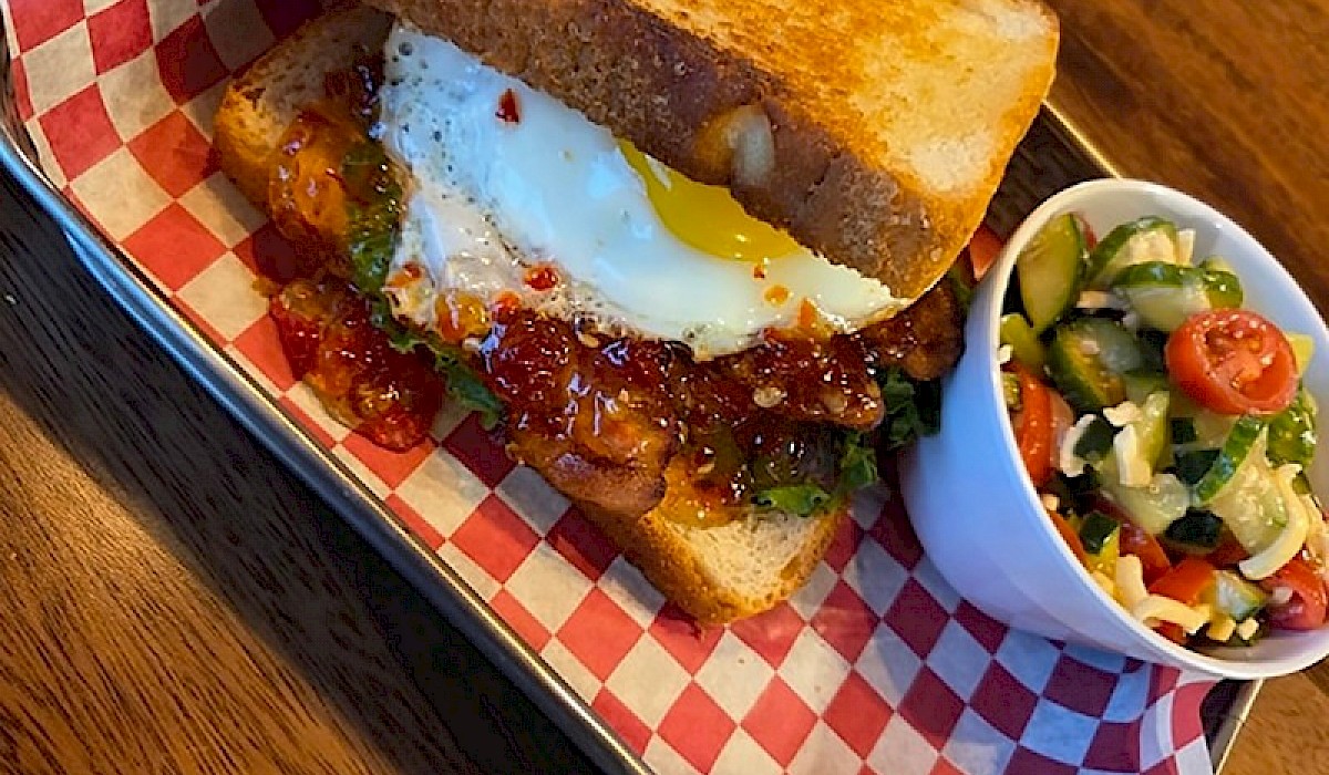 A egg BLT with a side of pasta salad sitting on a restaurant table