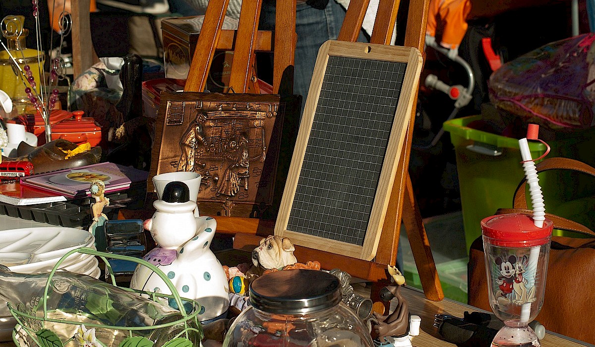 yard sale items, including wooden easels and nick nacks, arranged on a table during a yard sale