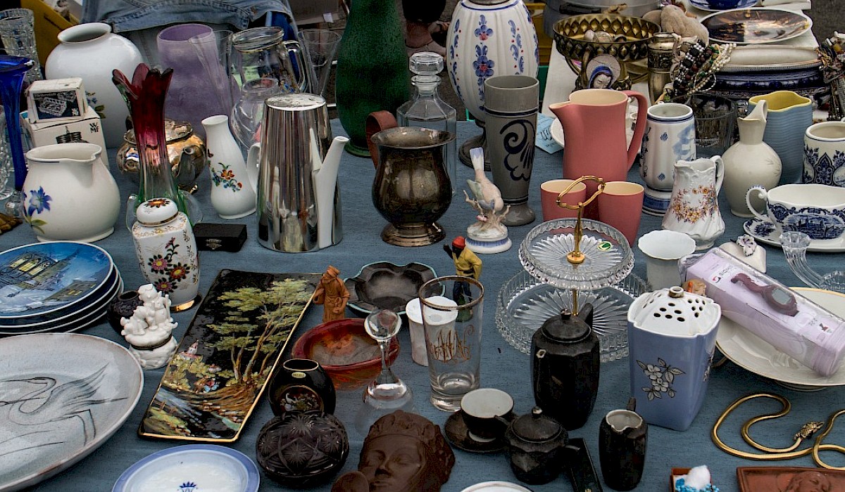 yard sale items on a table with a blue tablecloth outside during an event